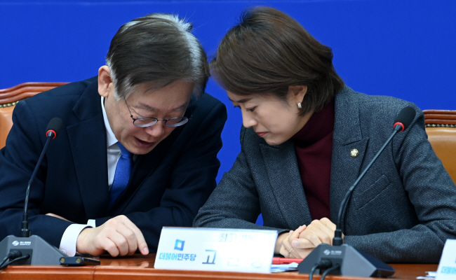 이재명(왼쪽) 더불어민주당 대표가 1일 오전 국회에서 열린 최고위원회의에 참석해 고민정 최고위원과 손가락으로 글씨를 써가며 이야기를 나누고 있다.   곽성호 기자