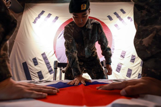 육군훈련소 훈련병이 지난 10일 충남 논산시 선샤인랜드에서 진행된 호국정신 계승 팀 미션 체험학습 중 태극기 위에 손도장을 찍고 있다. 국방일보 제공
