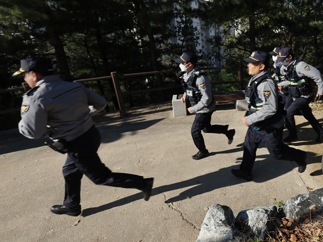 경찰관들이 21일 서울 성동구 달맞이봉공원에서 보행자가 휴대전화로 QR코드를 찍으면 관제센터로 실시간 공유되는 ‘산책로 범죄예방시스템’ 모의훈련을 진행하고 있다. 연합뉴스
