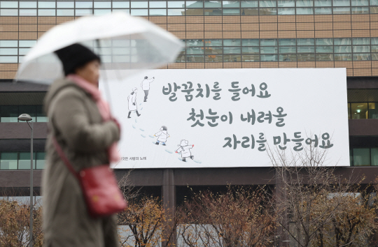 기온이 영상권을 회복한 27일 오전 서울 종로구 광화문광장 인근에 비가 내리자 시민이 비를 피하고 있다.연합뉴스