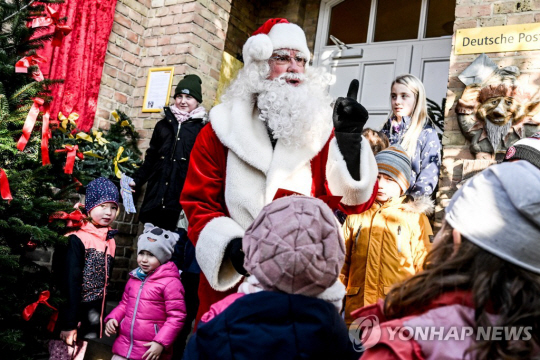 지난해 11월 15일(현지시간) 독일 힘멜포르트 우체국 앞에서 산타클로스 분장을 한 직원이 아이들을 맞이하는 모습. 연합뉴스.
