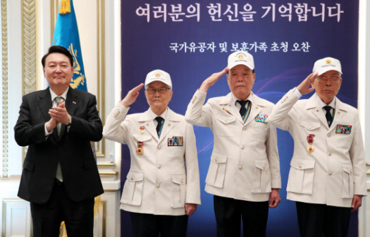 윤석열 대통령이 지난해 6월 14일 청와대 영빈관에서 열린 국가유공자 및 보훈가족 초청 오찬에서 대한민국 6·25참전유공자회 손희원 회장(왼쪽 두번째부터), 김창석· 이하영 이사에게 ‘영웅의 제복’을 직접 입혀준 뒤 기념촬영을 하고 있다. 연합뉴스