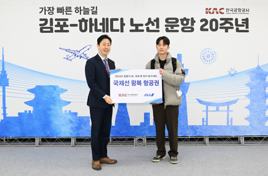 지난 1일 김포국제공항에서 윤형중(왼쪽) 한국공항공사 사장이 첫 국제선 이용객에게 김포-하네다 노선 왕복 항공권을 증정하고 있다. 한국공항공사 제공