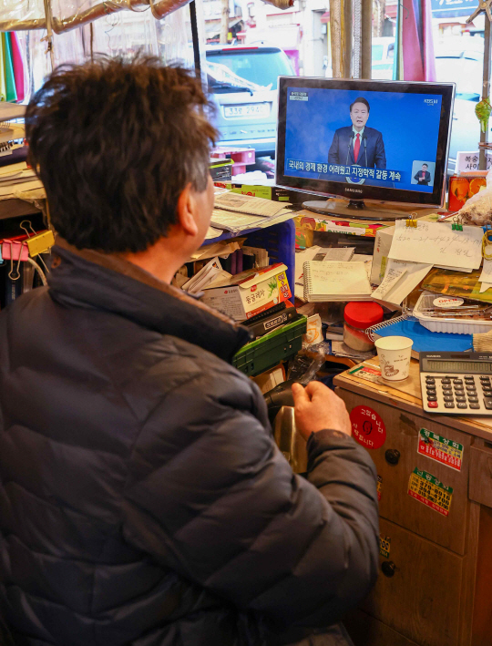 새해 첫날인 1일 오전 서울 시내 한 전통시장에서 한 상인이 윤석열 대통령의 2024년 신년사 방송을 지켜보고 있다. 연합뉴스