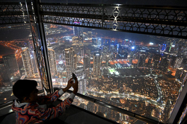 크리스마스인 지난해 12월 25일 아랍에미리트(UAE) 두바이의 부르즈 칼리파 전망대에서 한 관광객이 화려한 두바이 야경을 촬영하고 있다. 부르즈 칼리파는 삼성물산이 2010년 준공한, 높이 828m의 세계 최고층 빌딩이다. 문호남 기자