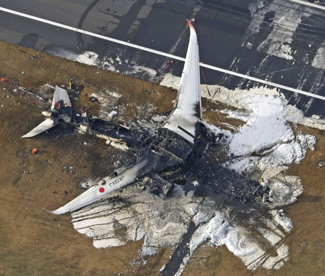 3일 일본 도쿄 하네다 공항 활주로에 전날 착륙 중 해상보안청 항공기와 충돌해 전소된 일본항공(JAL) 여객기 잔해가 흩어져 있다.  AP 연합뉴스