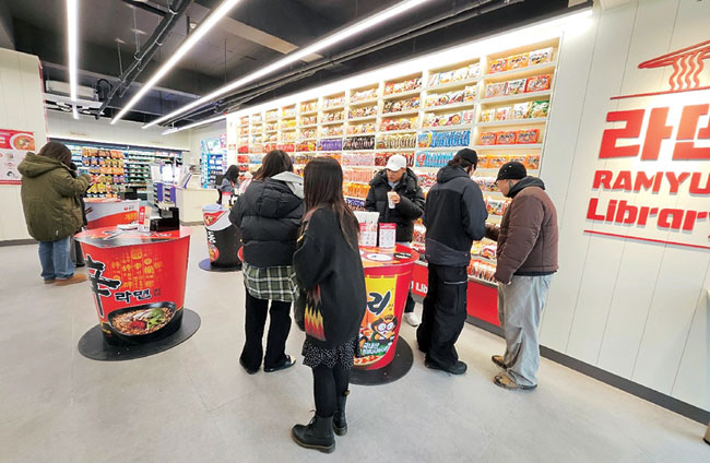 3일 서울 마포구에 위치한 라면 특화 편의점 CU 홍대상상점을 찾은 외국인들이 매장에 진열된 다양한 라면 제품을 살펴보고 있다.  CU 제공