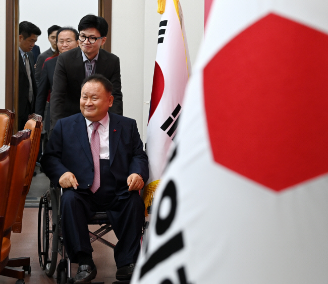 8일 오전 국민의힘에 입당한 이상민(유성을) 전 더불어민주당 의원이 국민의힘 당기와 태극기 사이로 한동훈 비상대책위원장이 밀어주는 휠체어에 앉아 비대위원 회의장으로 들어서고 있다. 곽성호 기자