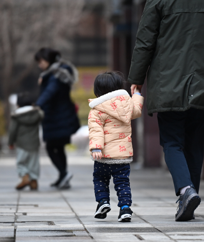 18일 오전 서울 영등포구 여의도에서 아이가 보호자의 손을 잡고 어린이집으로 향하고 있다. 국민의힘과 더불어민주당이 출생률을 끌어올리기 위해 정책경쟁에 나서고 있어 2022년 기준 0.78명인 합계출산율이 바닥을 치고 올라갈지 관심이 모아지고 있다.  박윤슬 기자
