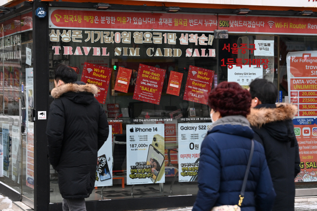 정부가 ‘단통법’으로 불리는 이동통신단말기 유통구조 개선법 폐지를 논의하고 있는 가운데 22일 오전 단말기 할인 광고로 도배된 서울 시내의 한 이동통신 대리점 앞을 시민들이 지나가고 있다.  문호남 기자