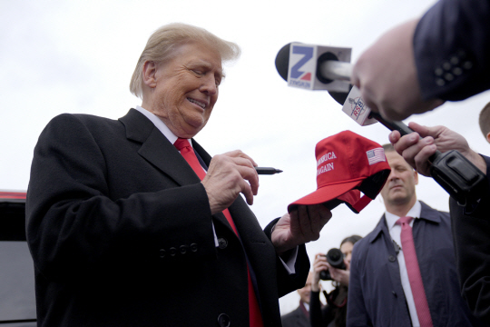미 공화당 대선 예비후보 도널드 트럼프 전 대통령이 23일(현지시각) 뉴햄프셔주 런던데리의 한 유세장에 도착해 모자에 서명하고 있다. [런던데리=AP/뉴시스]