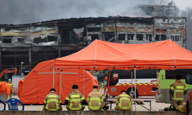 1일 오전 경북 문경시 신기동 육가공 업체 앞에서 소방대원들이 화재로 타버린 공장을 바라보고 있다. 전날 오후 이 공장에서 발생한 화재를 진압하는 과정에서 소방대원 2명이 순직했다.   뉴시스