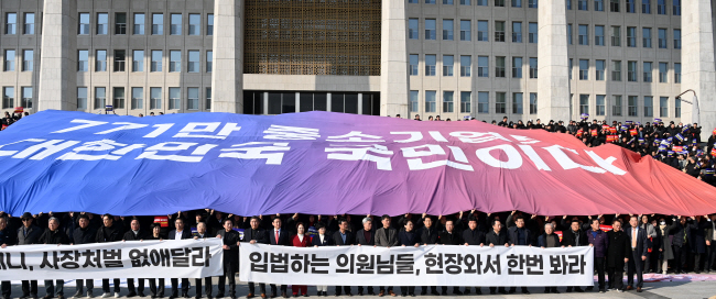 한국경영자총협회와 중소기업중앙회 관계자들이 지난달 31일 서울 영등포구 국회 본관 계단에서 ‘50인 미만 사업장 중대재해처벌법 유예 불발 규탄 대회’를 열고 초대형 펼침막을 손 위로 들고 있다.  곽성호 기자