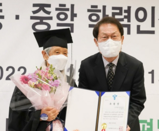 조희연 서울시교육감(오른쪽)이 지난 2022년 2월 서울 중구 바비엥2에서 열린 ‘2021학년도 초등·중등 학력 인정 문해교육 졸업식’에서 문해교육 프로그램을 이수한 최고령 만학도 신광천(95세) 할아버지에게 우등상을 수여한 뒤 기념 촬영하고 있다. 연합뉴스