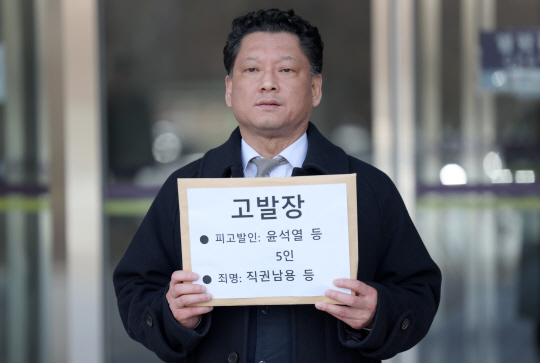 김한메 사법정의바로세우기시민행동 상임대표가 13일 경기 과천시 정부과천청사 고위공직자범죄수사처 앞에서 윤석열 대통령(전 검찰총장), 한동훈 국민의힘 비상대책위원장(전 대검찰청 반부패강력부장) 등에 대한 고발장을 들어 보이고 있다. 뉴시스