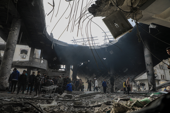 12일 이스라엘군 공습으로 지붕이 무너진 팔레스타인 가자지구 라파 지역 건물 내부를 관계자들이 살펴보고 있다. 이날 공습으로 가자지구 주민 최소 100명이 사망하고 160여 명이 부상을 입었다.  신화통신 연합뉴스