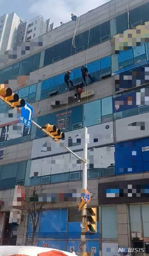 소방당국 구조대원들이 24일 경기 시흥시 한 상가건물 외벽 간판 위에 앉아 있던 치매 환자 A씨를 구조하고 있다. 경기도소방재난본부 제공. 뉴시스