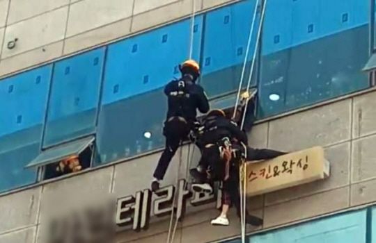 소방당국 구조대원들이 24일 경기 시흥시 한 상가건물 외벽 간판 위에 앉아 있던 치매 환자 A씨를 구조하고 있다. 경기도소방재난본부 제공. 연합뉴스
