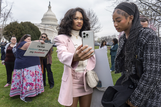 ‘틱톡 금지법안’에 반대하는 미국 시민들이 13일 워싱턴DC 국회의사당 앞에 모여 표결 결과를 확인하고 있다. 이날 미국 연방 하원은 틱톡 금지법안을 352표, 반대 65표의 압도적 표차로 통과시켰다.  AP 연합뉴스