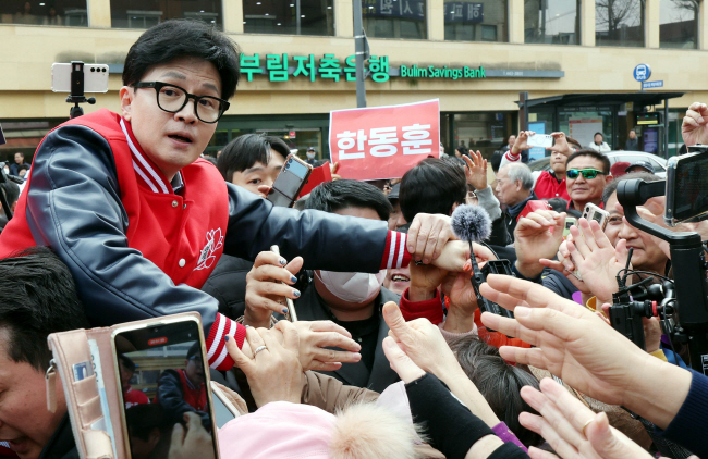 한동훈(왼쪽) 국민의힘 비상대책위원장 겸 총괄선대위원장이 20일 안양중앙시장을 방문, 지지자들의 환호에 답하며 인사를 하고 있다. 연합뉴스