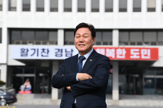 박완수 경남지사가 지난 12일 민선 8기 캐치프레이즈로 도청 현관에 내건 ‘활기찬 경남 행복한 도민’ 문구 앞에서 환하게 웃고 있다.  문호남 기자