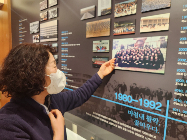 17세 때 한일합섬에 입사해 일과 공부를 병행하며 한일여고를 졸업한 뒤 현재 한일여고에서 근무하고 있는 10회 졸업생인 김영심 씨가 학교 1층에 조성된 ‘50년관’에서 선배들의 졸업사진을 살펴보고 있다.