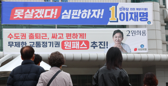 28일 인천 계양역 앞에 걸린 이재명 더불어민주당·원희룡 국민의힘 후보의 현수막. 민주당은 ‘정권심판’을, 국민의힘은 정책 내용을 현수막에 담았다. 연합뉴스