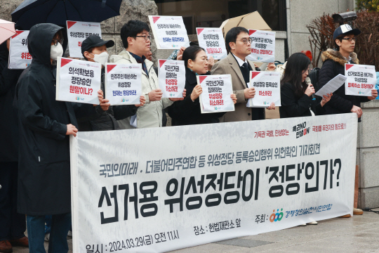 경제정의실천시민연합 관계자들이 29일 서울 종로구 헌법재판소 앞에서 ‘위성정당(국민의미래·더불어민주연합) 정당등록 위헌확인 헌법소원 및 효력정지 가처분신청 기자회견’을 하고 있다. 연합뉴스
