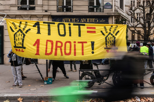 지난해 12월 프랑스 파리의 프랑스 주택부 앞에서 사람들이 ‘지붕은 권리다’라고 적힌 현수막을 들고 달로 법 적용을 요구하고 있다. EPA 연합뉴스