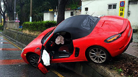 지난달 28일 광주 북구 신안동 신안교 인근 편도 3차선 도로에서 포르쉐가 인도로 올라간 채 버려져 있다. 뉴시스