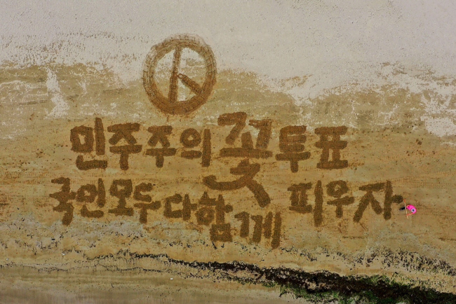서예가 김동욱 씨가 8일 오전 경북 포항 송도해수욕장 모래사장에 투표를 독려하는 대형글씨를 쓰는 퍼포먼스를 하고 있다. 연합뉴스