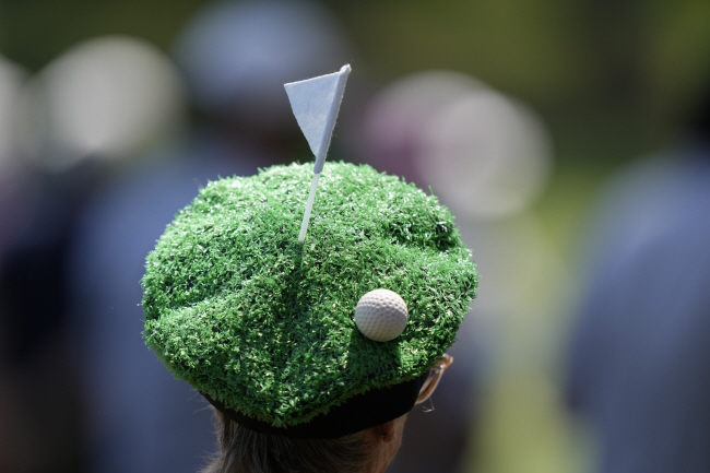 그린 위의 공을 표현한 이색 모자를 쓴 한 패트론이 마스터스 연습 라운드 첫날 12번 홀에서 선수들을 기다리고 있다.  AP 연합뉴스