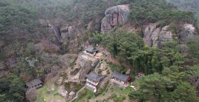 곡성 오산면의 절집 용주사. 마치 ‘무협지 속 공간’처럼 느껴지는 자리에 있다. 법당 뒤로 병풍처럼 서 있는 크고 기이한 근육질의 바위가 인상적이다. 사진 왼쪽의 바위에는 물길을 돌려서 만든 폭포가 실타래처럼 걸려있다.