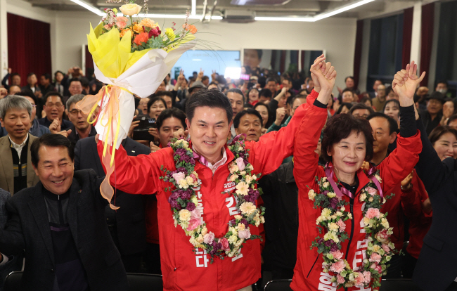 김태호(가운데) 국민의힘 경남 양산을 후보가 11일 오전 양산시 자신의 선거사무소에서 ‘당선 확실’이 뜨자 아내 신옥임씨와 손을 들고 지지자에게 인사하고 있다.  연합뉴스