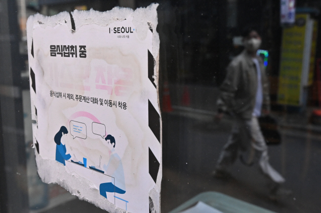 내달 1일부터 코로나19 위기단계가 가장 낮은 단계인 ‘관심’으로 하향되면서 병원급 의료기관 마스크 착용 의무가 권고로 전환되는 등 완전한 일상 회복으로 돌아간다. 19일 오전 서울 종로구 먹자골목 내 한 음식점 벽면에 뜯어지다 만 마스크 착용 의무 안내문이 붙어 있다.  백동현 기자