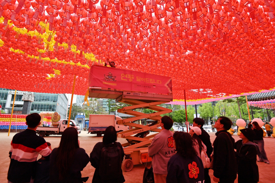 불기 2568년 부처님 오신 날(5월15일)을 앞둔 21일 서울 종로구 조계사를 찾은 불자들이 형형색색의 연등에 소원지를 붙이는 모습을 보고 있다. 문호남 기자