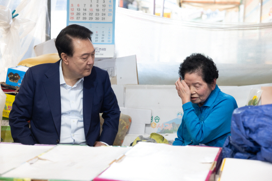 윤석열 대통령이 취임 2주년을 맞은 10일 서울 서대문구 영천시장을 찾아 과일가게 90대 상인과 대화하며 고충을 경청하고 있다. 대통령실 제공