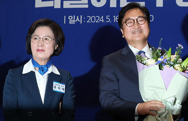 우원식(오른쪽) 더불어민주당 의원이 지난 16일 국회의원회관에서 열린 제22대 국회 전반기 국회의장단 후보 선출 당선자 총회에서 국회의장 후보로 선출된 뒤 축하 꽃다발을 받아들고 있다. 왼쪽은 이날 낙선한 추미애 국회의원 당선인. 뉴시스