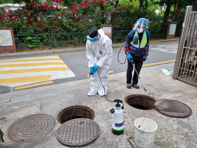 문화일보 김군찬(왼쪽) 기자가 20일 서울 광진구 구의공원 인근 주택가에서 모기 유충 방제 작업을 하고 있다. 광진구청 제공