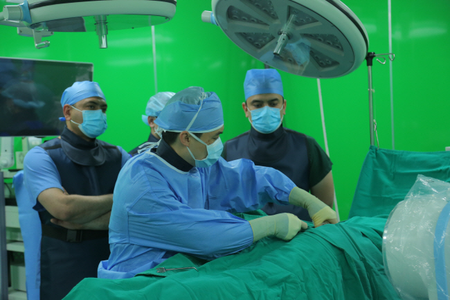 허준영(가운데) 목동힘찬병원 원장이 지난 2일 부하라 힘찬병원에서 신경성형술을 집도하며 현지 의료진에게 시술법을 전수하고 있다.  힘찬병원 제공