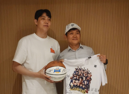 프로농구 부산 KCC의 정창영(왼쪽)과 김학남 현대코퍼레이션 두바이 지사장이 10일(한국시간) 아랍에미리트 두바이의 한 식당에서 만나 사인공과 우승 기념 티셔츠를 선물하고 있다. 뉴시스