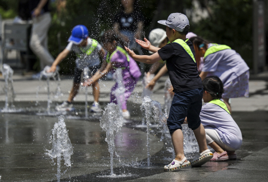 낮 최고기온이 35도로 더운 날씨를 보인 14일 서울 종로구 광화문광장을 찾은 어린이들이 물놀이를 하며 더위를 식히고 있다. 사진 뉴시스