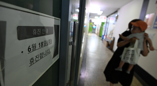 의대 증원에 반발하는 대한의사협회 주도로 개원의들이 18일 하루 집단 휴진을 벌인 가운데 이날 오전 서울 여의도 한 소아청소년과 의원 앞에서 한 아이와 엄마가 휴진을 알리는 안내문을 보고 발걸음을 돌리고 있다.  박윤슬 기자