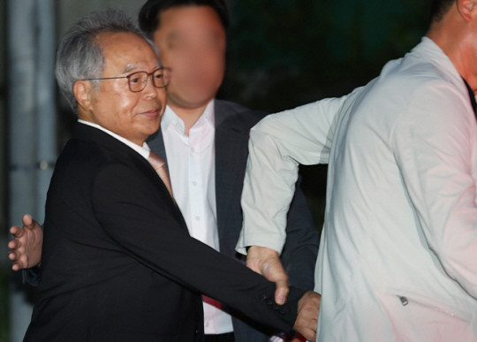 오거돈 전 부산시장이 26일 오전 만기 출소로 풀려나 부산 사상구 부산구치소를 나서고 있다. 취재진 질문이 이어지자 오 전 시장의 지인은 그의 손을 이끌고 차량에 빠르게 태웠다. 연합뉴스