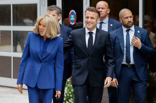 에마뉘엘 마크롱(사진 오른쪽) 프랑스 대통령이 7일 브리지트 여사와 함께 총선 결선 투표를 위해 르 투케에 마련된 투표소로 들어가고 있다.  AFP 로이터 연합뉴스