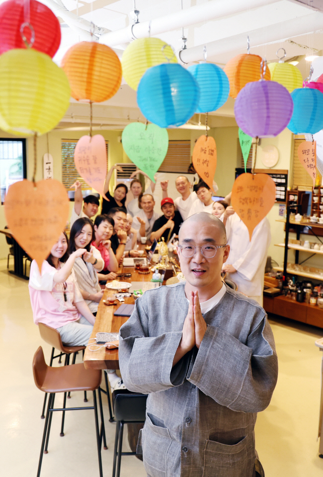지난 8일 서울 서대문구 신촌로에 자리한 ‘명상 게스트하우스’ 저스트비에서 만난 준한 스님(맨 앞)이 합장하고 있다. 그 뒤에 선원을 함께 이끄는 여러 스님과 다양한 국적의 직원들이 손가락 하트 등 각자의 방식으로 인사하고 있다. 윤성호 기자