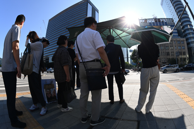 수도권에 폭염과 소나기가 예보된 15일 오전 서울 종로구 세종대로 사거리에서 시민들이 그늘에서 보행 신호를 기다리고 있다. 문호남 기자