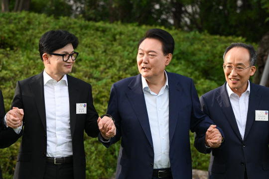 윤석열 대통령이 24일 서울 용산 대통령실 청사에서 국민의힘 신임 당 지도부 만찬에 앞서 한동훈 신임 당대표와 추경호 원내대표를 비롯한 당 지도부와 기념촬영하며 손을 잡고 있다. 뉴시스