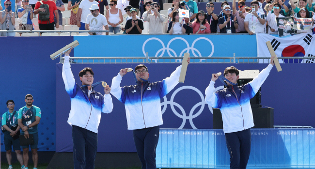 2024 파리올림픽 양궁 남자 단체전에서 금메달을 딴 이우석(왼쪽부터)과 김우진, 김제덕이 30일 프랑스 파리 레쟁발리드에서 열린 시상식에서 환호하는 관중을 향해 금메달과 기념품을 들어 보이며 인사를 하고 있다.  윤성호 기자