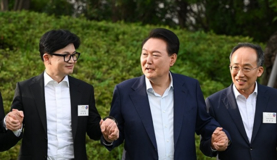 윤석열 대통령이 24일 서울 용산 대통령실 앞 파인그라스에서 열린 국민의힘 신임 지도부 만찬에서 한동훈 대표(왼쪽), 추경호 원내대표(오른쪽) 등과 함께 손을 맞잡고 기념 촬영을 하고 있다. 대통령실 제공.